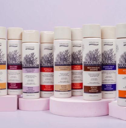 Row of Colournance hair care products on pink stands against a light purple background