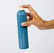 Hand holding a blue spray bottle labeled 'Davroe' against a white background