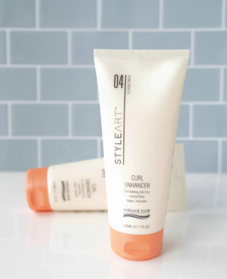 Two bottles of StyleArt hair care products on a white surface with a gray tiled wall background.