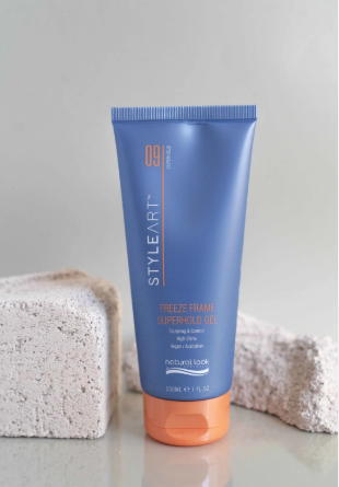Blue tube of hair product on a gray surface with a textured background