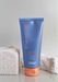 Blue tube of hair product on a gray surface with a textured background