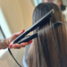 Person using a hair straightener on another person's hair